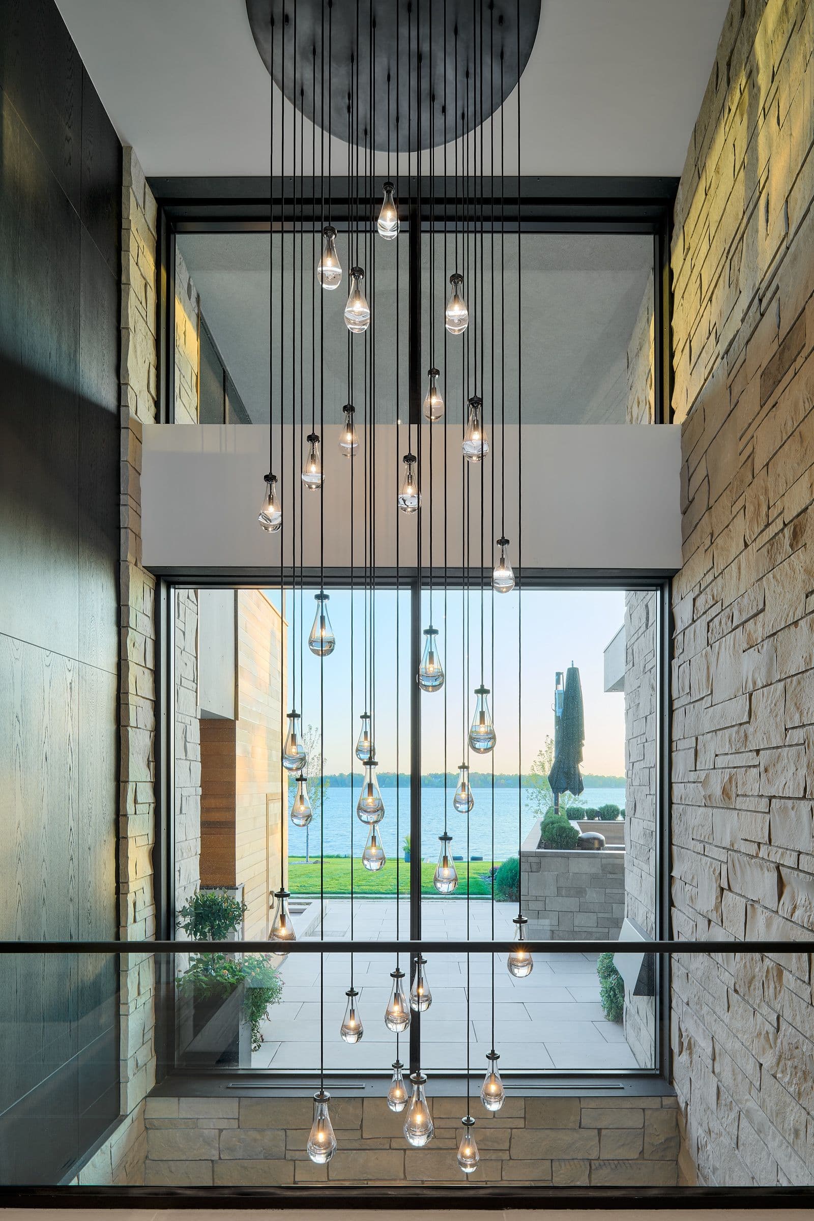 Cascading crystal chandelier in double-height entry with lakefront views