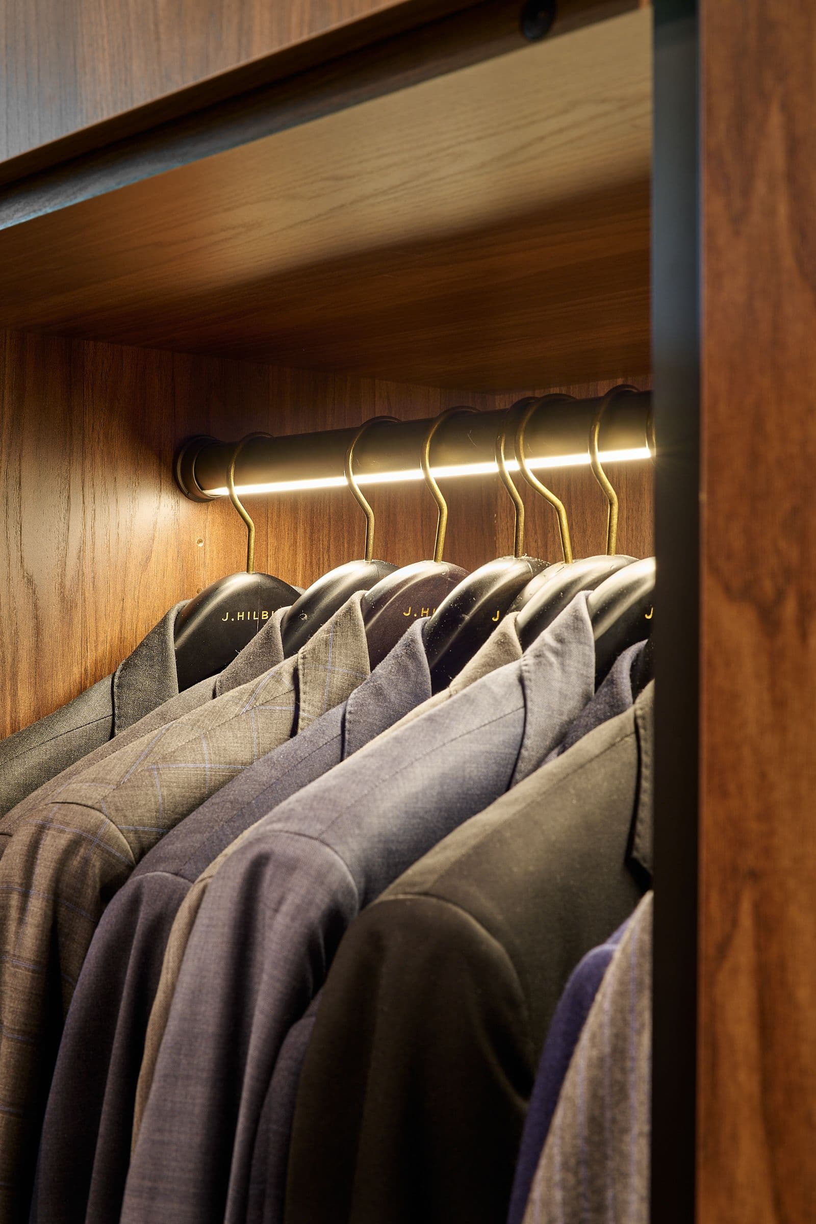 LED strip lighting integrated into custom closet hanging rods