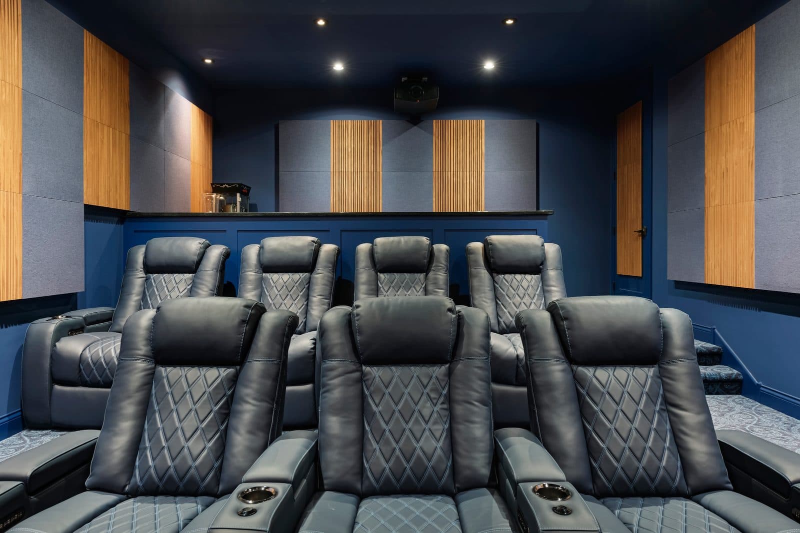 Diamond-quilted leather theater recliners with ceiling-mounted projector and acoustic treatments