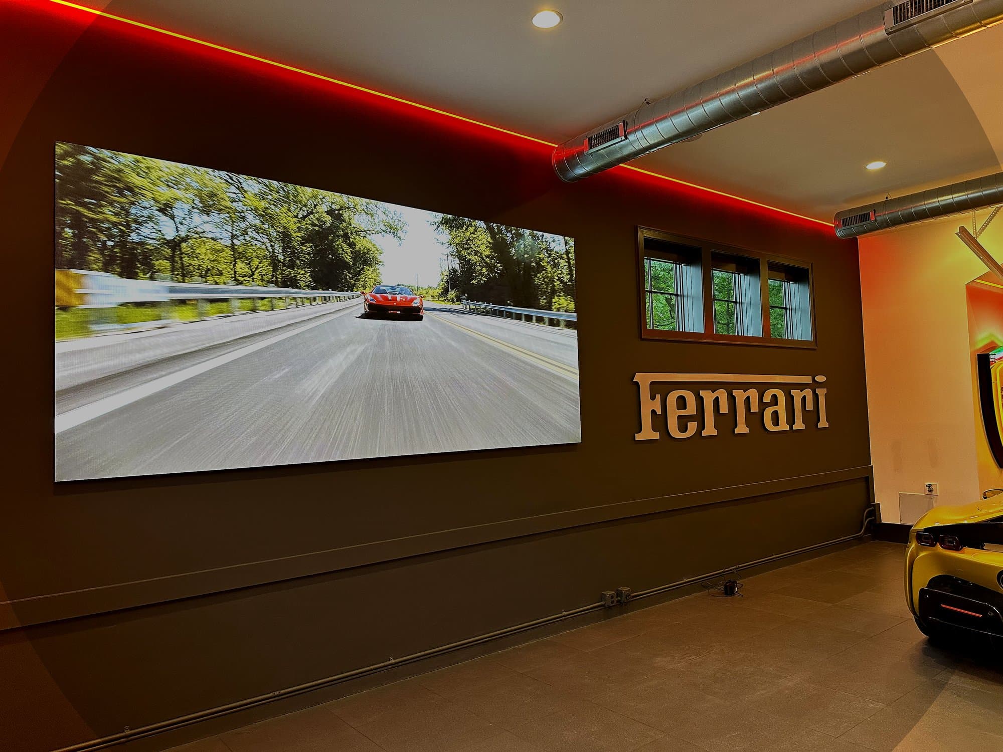 LED video wall displaying Ferrari content in luxury garage with ambient red accent lighting