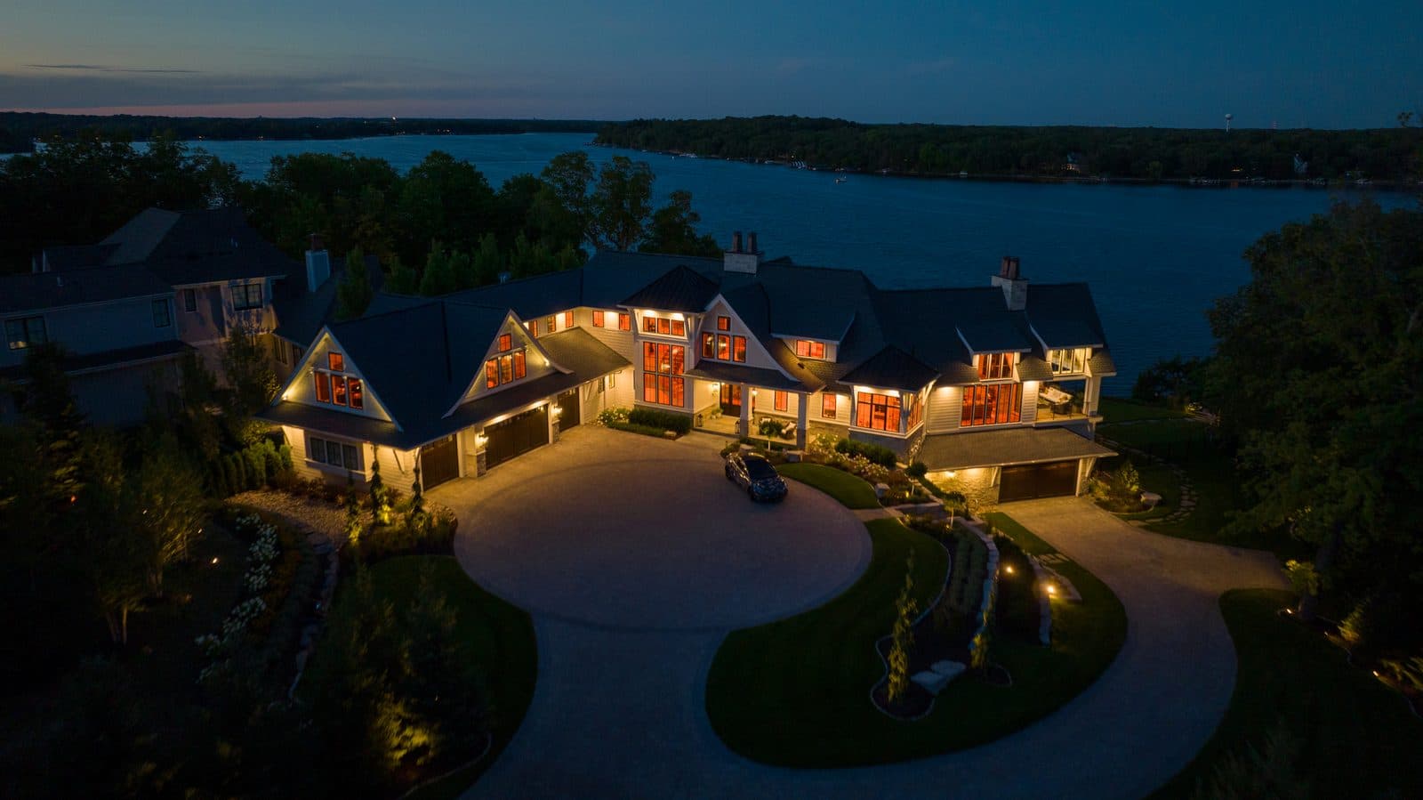 Aerial twilight view of lakefront estate with landscape accent lighting